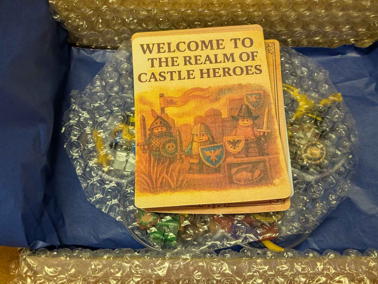 Card with 'Welcome to the Realm of Castle Heroes' text on a blue surface with bubble wrap.