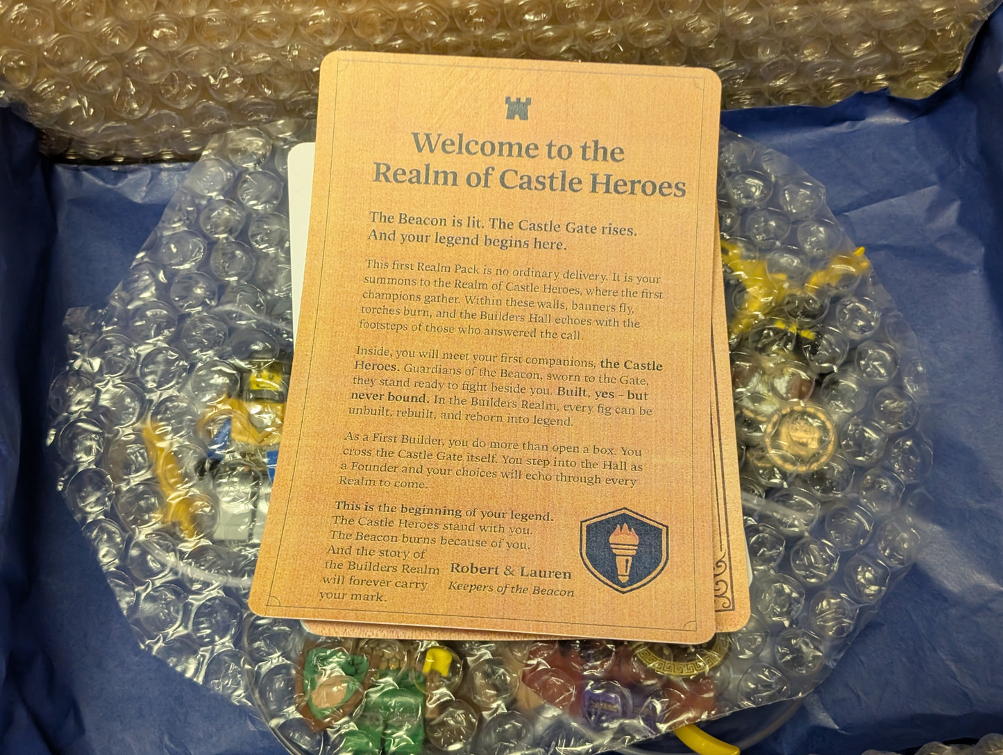 Card with 'Welcome to the Realm of Castle Heroes' text on a blue surface with small figurines.