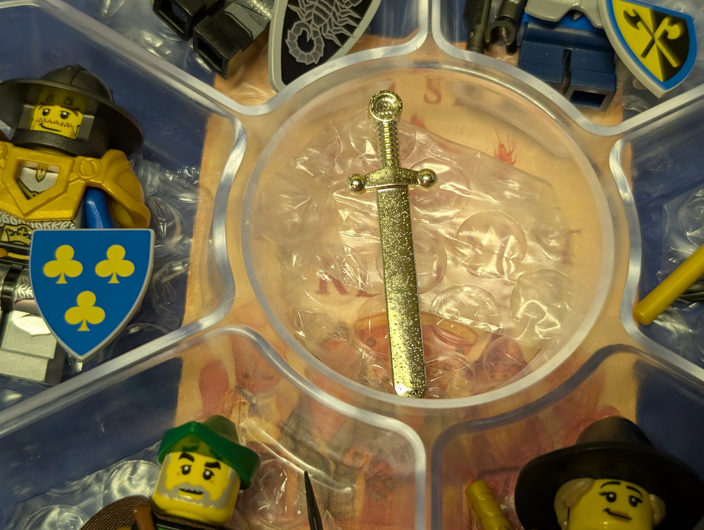 Toy sword in a clear plastic holder with toy figures around it.
