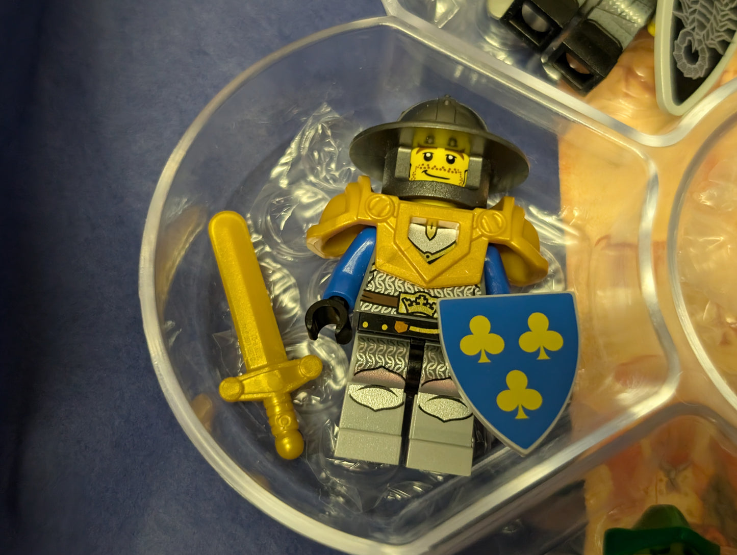 LEGO figure with a shield and sword in a clear container on a blue background